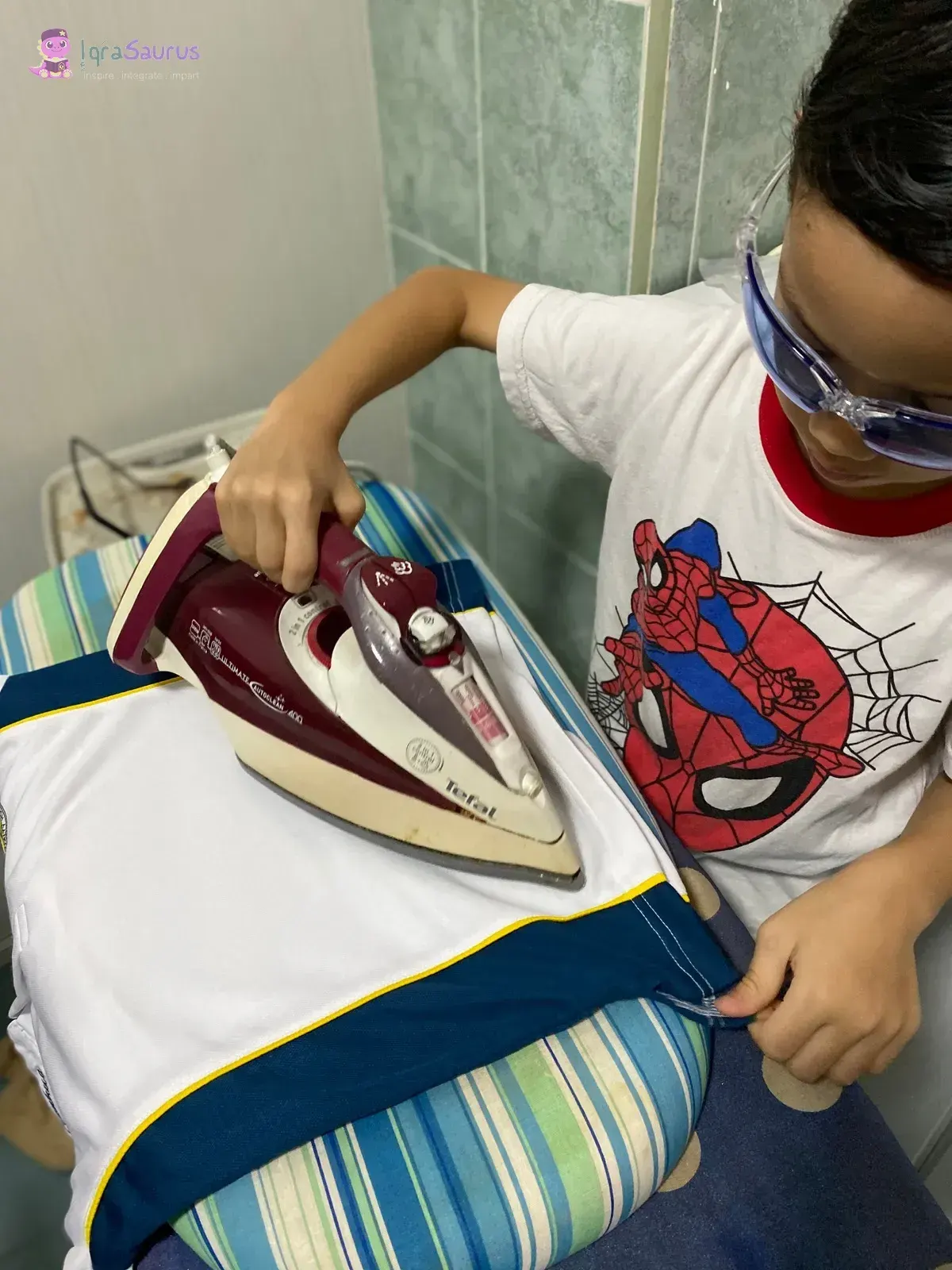 A boy in safety glasses irons a shirt on an ironing board