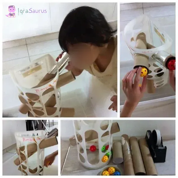 Hilwaa as a toddler looking into a home-made ball run of cardboard tubes and coloured balls, face blurred