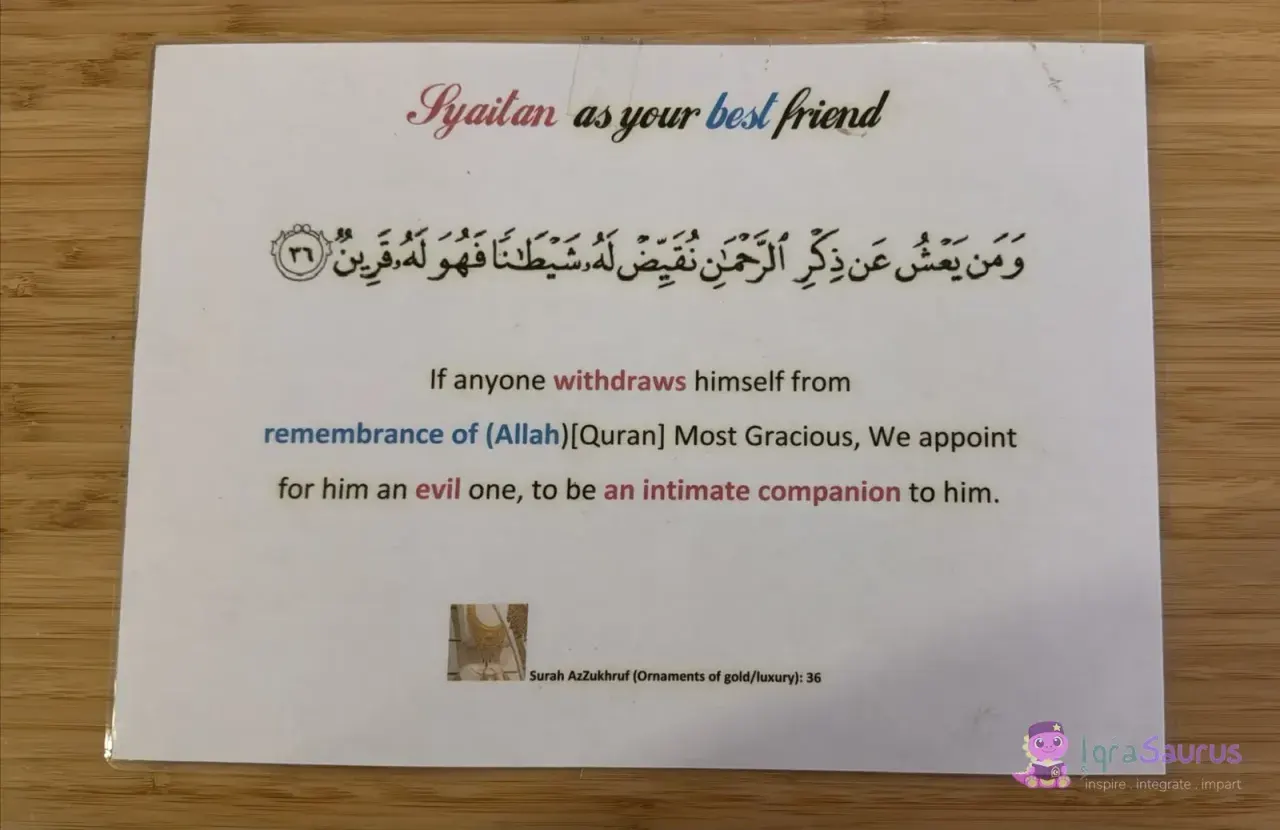 A laminated card headed "Syaitan as your best friend" with a verse from Surah Az-Zukhruf in Arabic and English