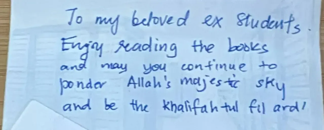 A handwritten note from a teacher to former students on the back of a small card